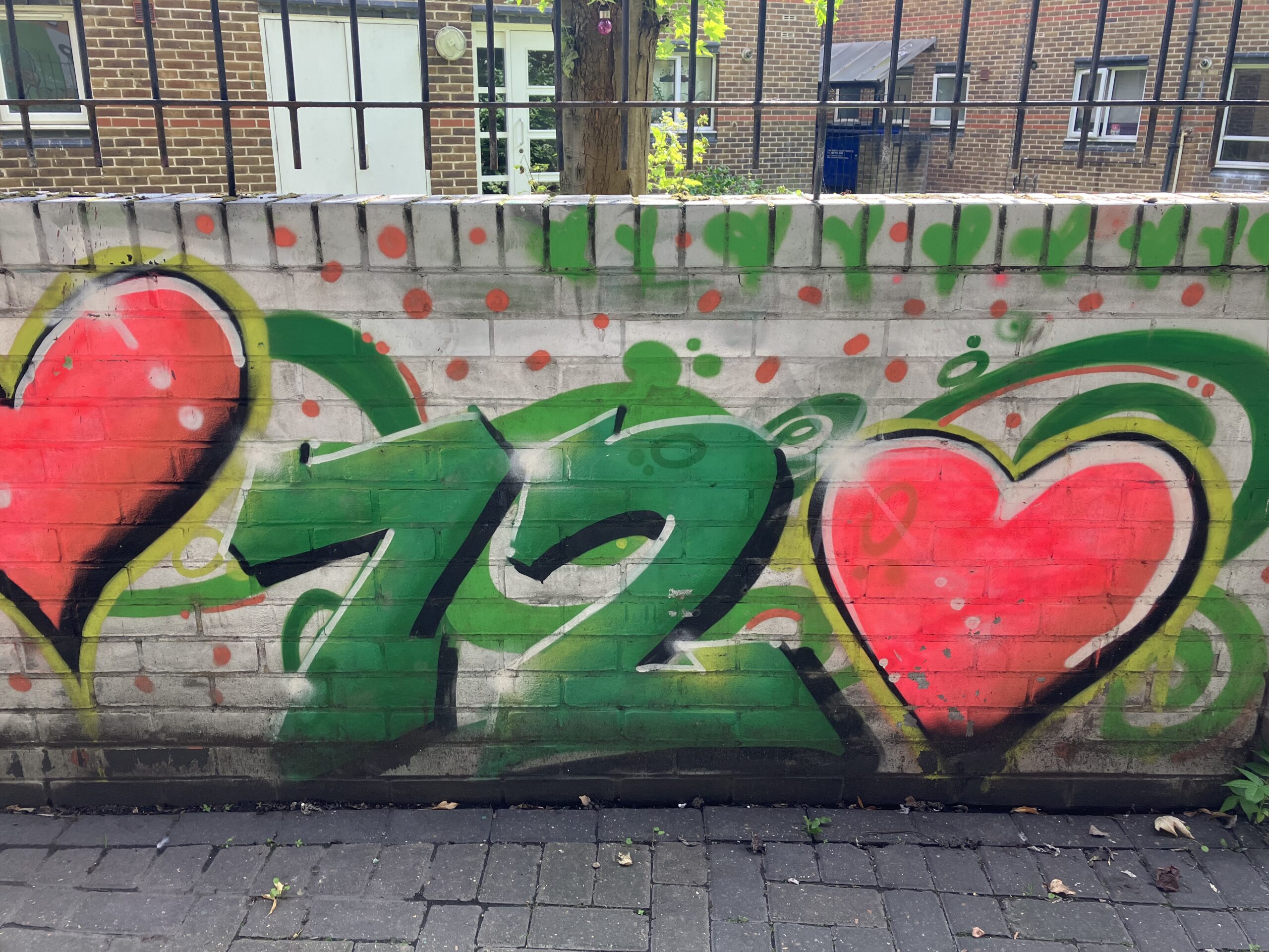 Number 72 graffitied on a wall with hearts next to it
